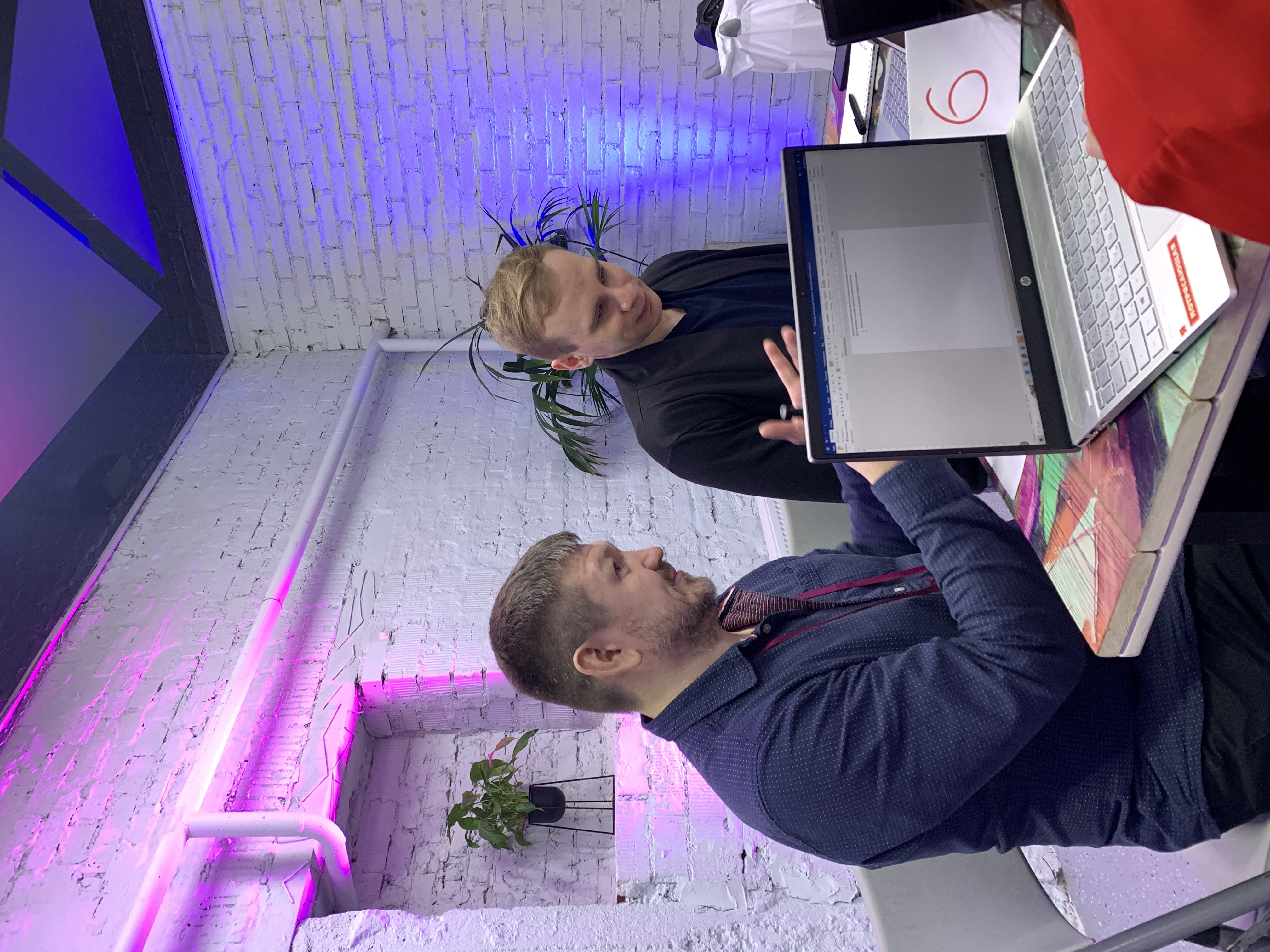 Сергей Красакович обсуждает задачу с участником за столом с ноутбуками