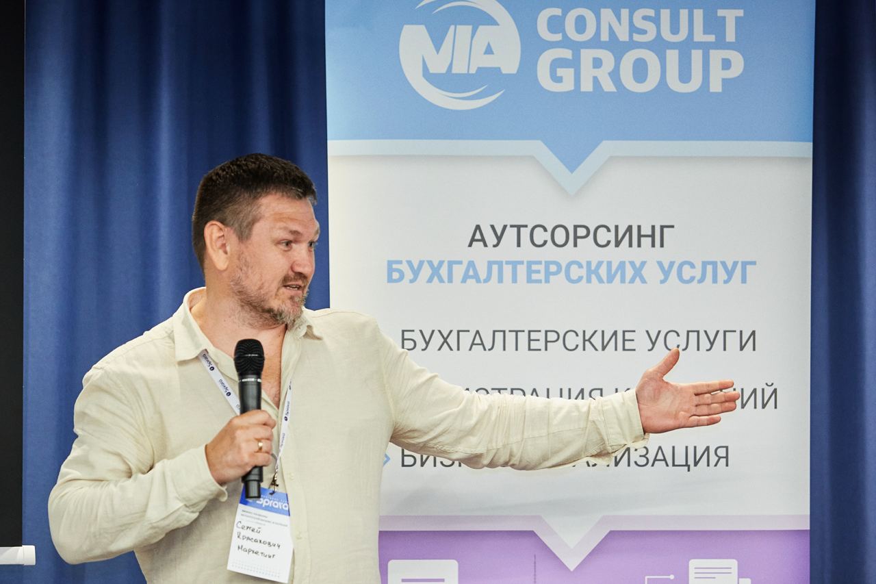 Сергей Красакович выступает с микрофоном и обращается к аудитории